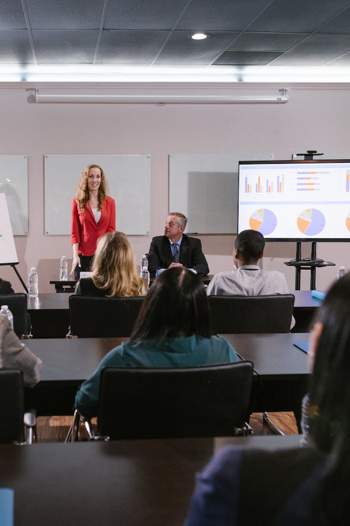 A diverse group of professionals attending a conference presentation with charts displayed.